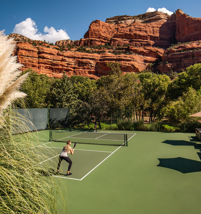 Pickleball court, two players, red rock formations surrounding the court.