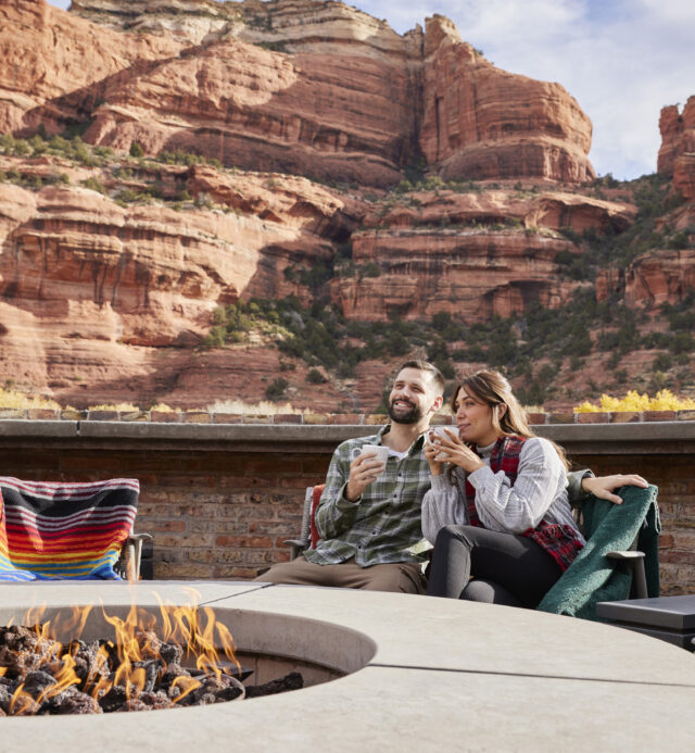 two people around firepit with red rocks in background