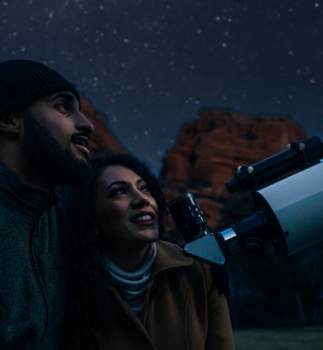 two guests looking into telescope during stargazing session in the winter at Enchantment